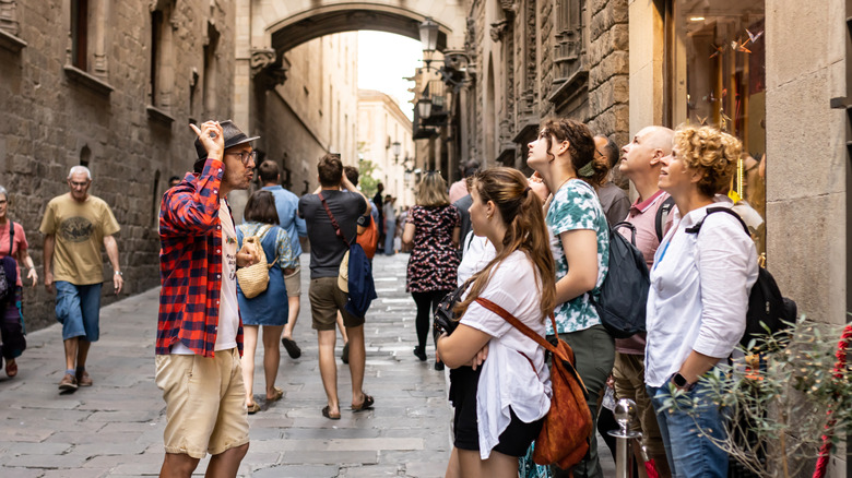 tour guide speaking to a group of tourists on a street with brigh buildings