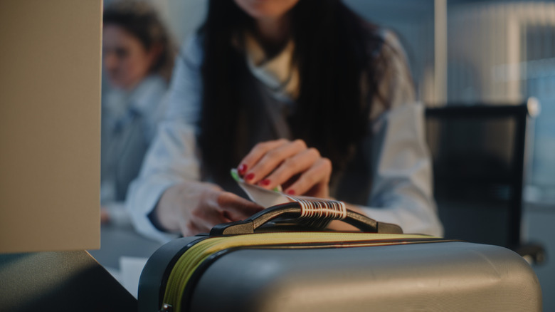 person putting luggage tag barcode on a suitcase